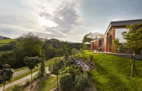 Moderne Unterkunft in gr&uuml;ner Landschaft mit Sonnenschirmen und Garten.