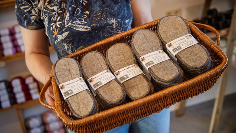 Person holding a basket of felt shoe insoles in a farm store.