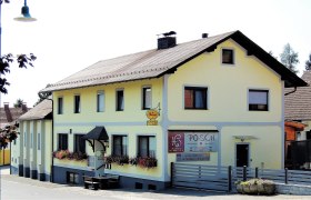 Gelbes Gasthaus mit Blumenkästen und Schild 'Posch'.