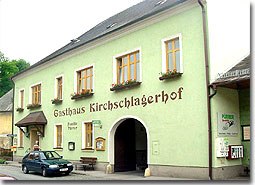 Ein traditionelles Gasthaus mit grüner Fassade und der Aufschrift 'Gasthaus Kirschlagerhof'.