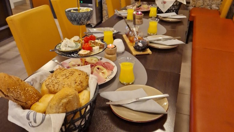 Frühstückstisch mit Brötchen, Aufschnitt und Orangensaft in einem Café.