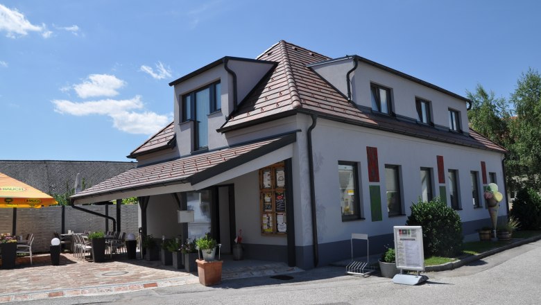 A modern building with a terrace and parasol on a sunny day.