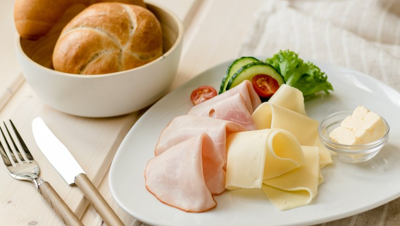 Fr&uuml;hst&uuml;cksteller mit Schinken, K&auml;se, Gem&uuml;se und Br&ouml;tchen.