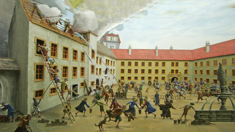 Diorama einer historischen Feuerwehrszene mit Zinnfiguren in einem Innenhof.