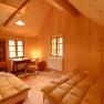 Holzvertäfeltes Zimmer mit zwei Betten, Schreibtisch und Stuhl.