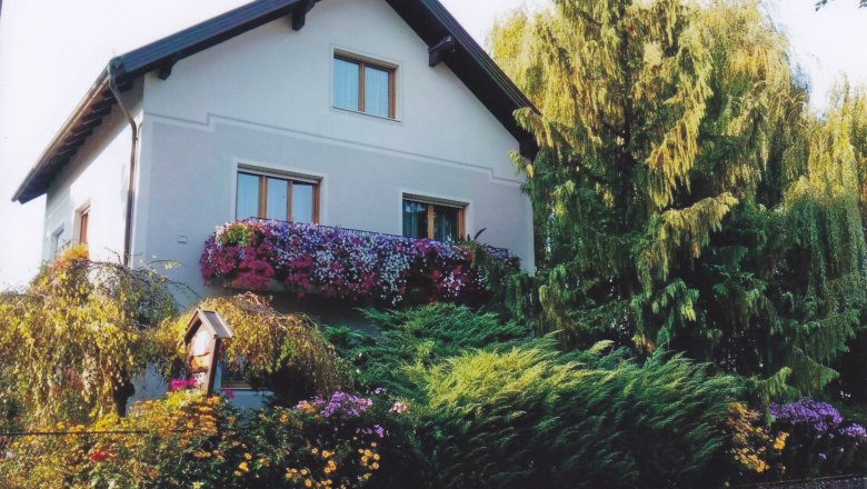 Privatzimmer Familie Kremsl, © Familie Kremsl Ein zweistöckiges Haus mit Blumen auf dem Balkon und umgeben von Bäumen und Sträuchern.