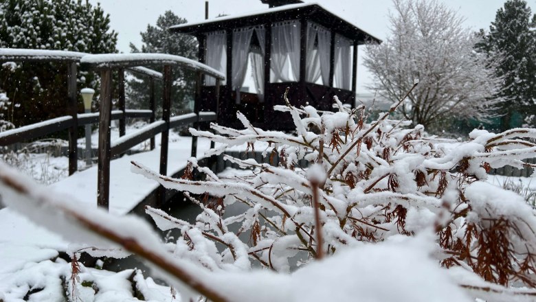 Verschneiter Zen-Garten mit Holzbr&uuml;cke und Pavillon im Hintergrund.