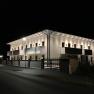 Beleuchtetes Gebäude bei Nacht mit Balkonen und Straßenlaternen.