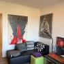 Living room with artwork on the walls, black sofa and colorful cushions.