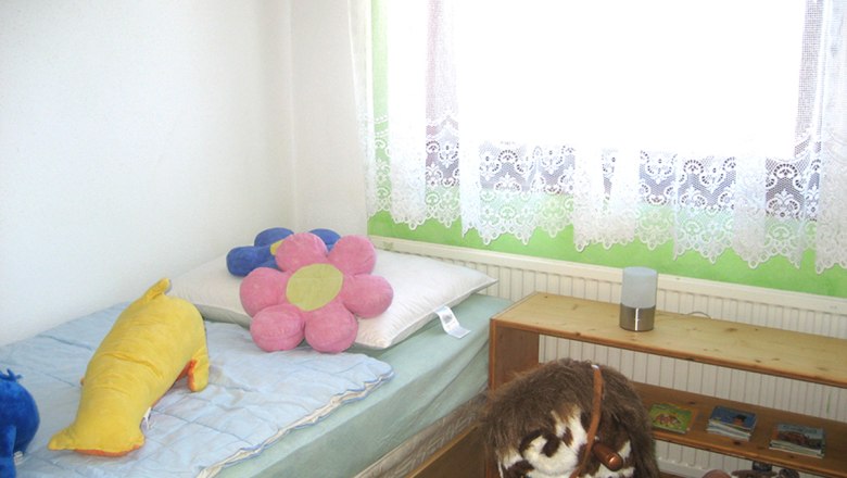 Kinderzimmer mit Bett, Pl&uuml;schtieren und Spielzeugpferd.