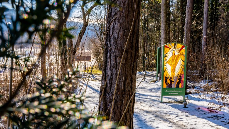 Winterlicher Waldweg mit Sonne und religiösem Bild aus Glas.