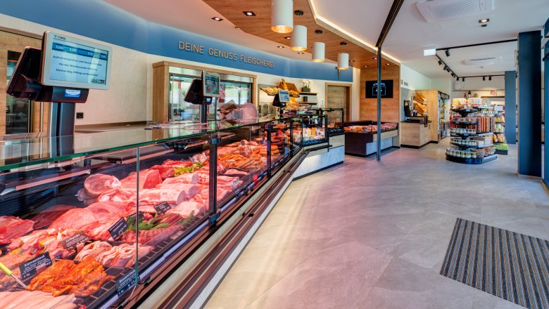 Verkaufsraum einer Fleischerei mit Vitrinen mit Fleisch und Wurstprodukten und Regalen.