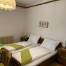 Cozy double room with two single beds, wooden furniture and a decorative lamp.