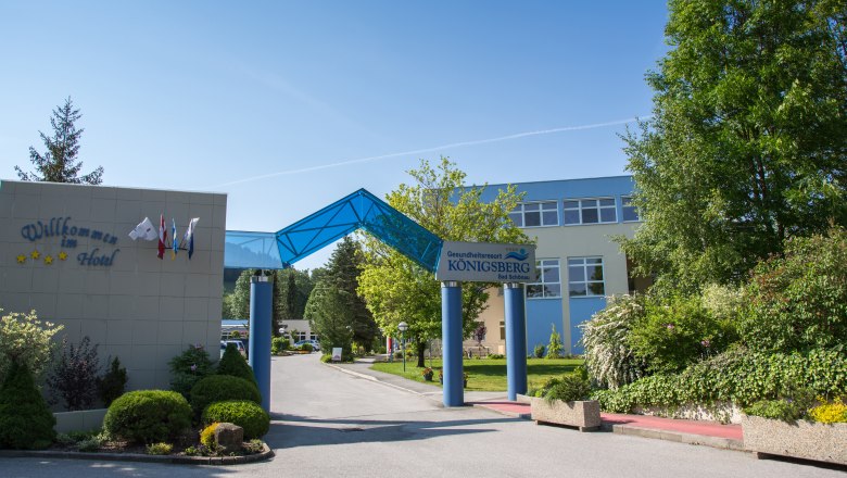 Einfahrt des Gesundheitsresorts Königsberg mit blauem Vordach und Begrüßungsschildern.