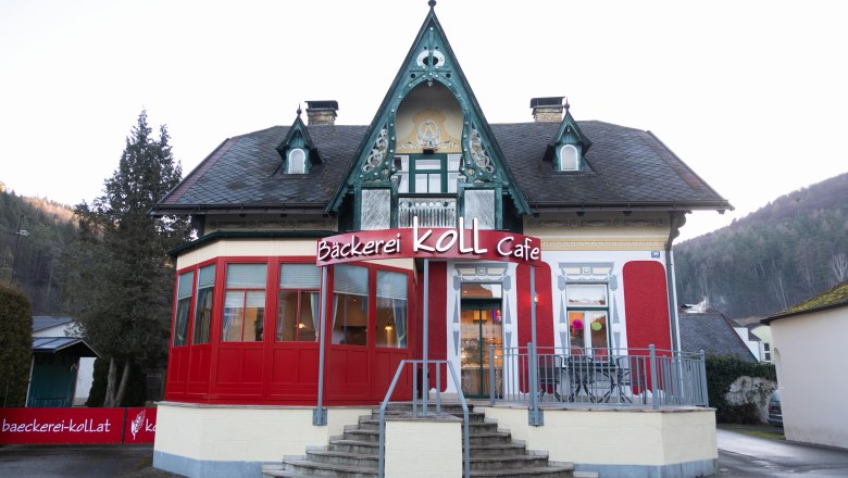 Bäckerei Koll Café in einem historischen Gebäude mit roter Fassade und dekorativem Giebel.