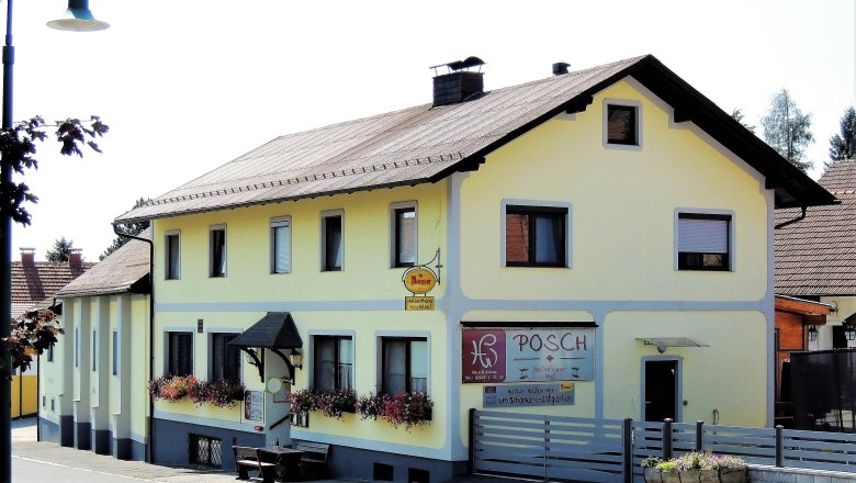 Gelbes Gasthaus mit Blumenkästen und Schild 'Posch'.