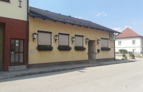 Außenansicht eines gelben Gasthauses mit geschlossenen Fensterläden und Blumenkästen.