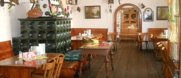 Interior view of a traditional Austrian wine tavern with wooden furniture and tiled stove.