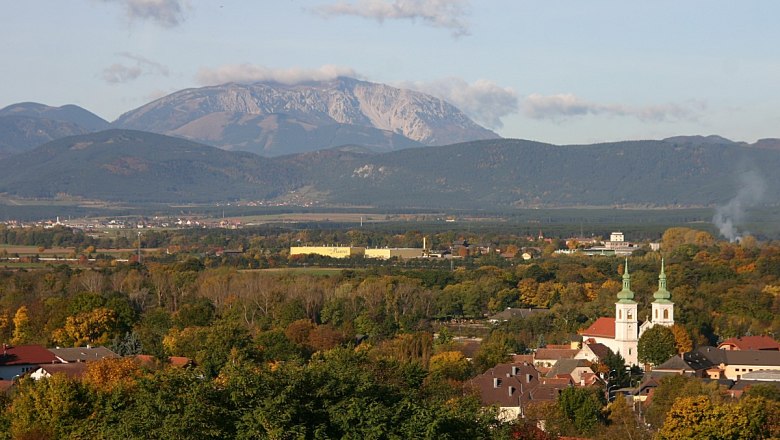 Panorama von Schwarzau am Steinfeld mit Kirche und Bergen im Hintergrund.