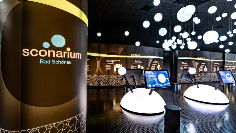 Interior view of the Sconarium exhibition in Bad Schönau with interactive displays and illuminated spheres on the ceiling.