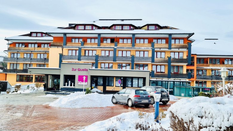 Vivea 4* Hotel Bad Schönau Zur Quelle, © Wiener Alpen Hotelgebäude "Zur Quelle" mit bunter Fassade im Winter und geparkten Autos im Vordergrund.