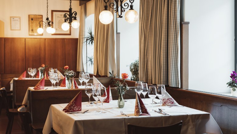 Cozy restaurant with laid tables, wine glasses and flower vases.