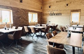 Gemütlicher Gastraum aus hellem Holz mit braunen Stühlen und Holztischen.