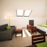 Helles Apartment mit Dachfenstern, Sofa, Bett, TV und Esstisch.