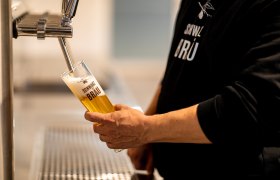 Eine Person zapft Bier in ein Glas mit der Aufschrift "Schwarzbr&auml;u".