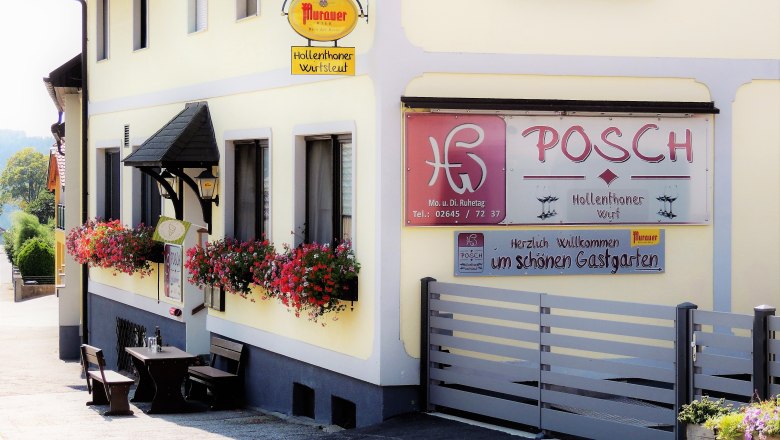 Außenansicht des Gasthauses Posch mit Blumen und Sitzgelegenheiten.