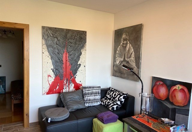 Living room with artwork on the walls, black sofa and colorful cushions.