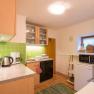 Small kitchen with green tiles, electrical appliances and wooden cupboards.