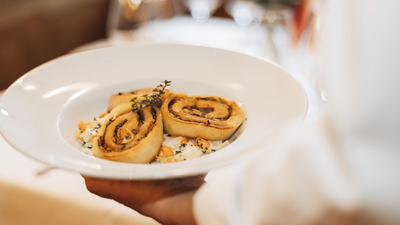 A plate of porcini mushroom roulades garnished with herbs is served.