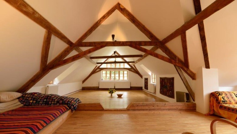 Ein heller Seminarraum mit Holzbalken, Holzboden und gemütlichen Sitzgelegenheiten.