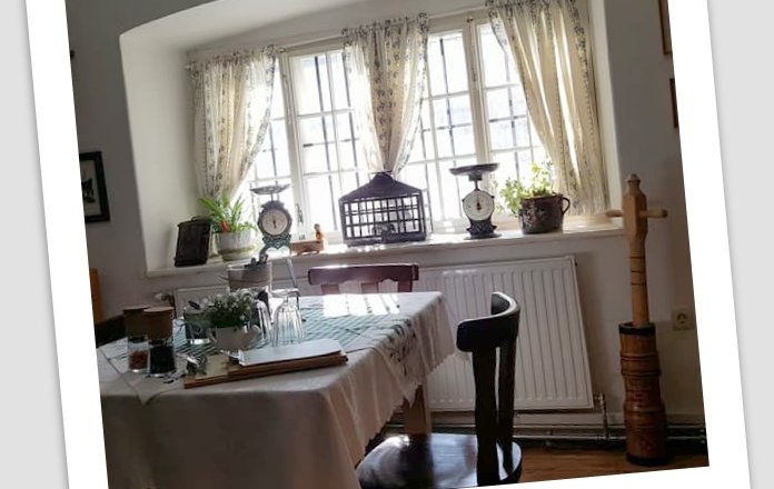 Gemütlicher Essbereich mit Tisch, Stühlen und Fenster mit Vorhängen.