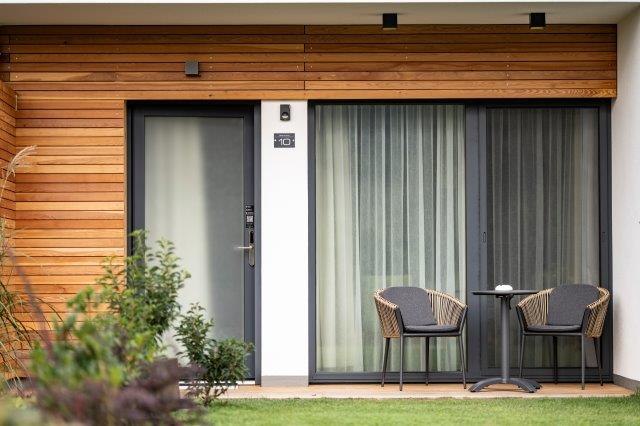 Moderne Terrasse mit zwei St&uuml;hlen und einem Tisch vor einem G&auml;stehaus.